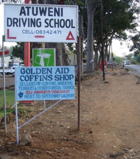 One of the ubiquitous coffin-shop signs. We're now walking out of town along a pleasant tree-lined road which curves down to the left.