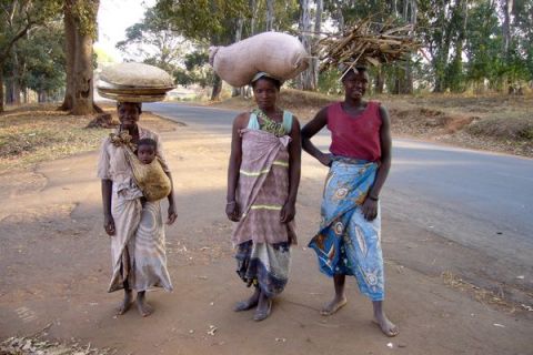 The road has curved to the left and is now heading slightly downhill. I pass these ladies carrying wood, maize flour and a baby. They too liked being photographed.